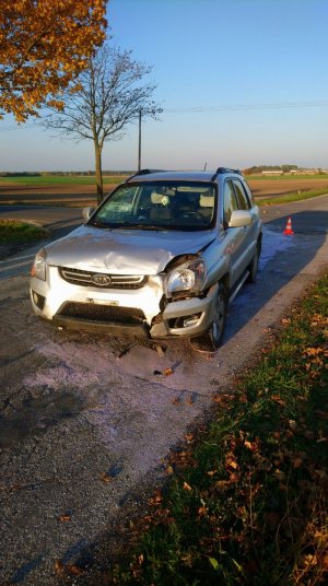 Samochód marki KIA, który został uszkodzony w rezultacie kolizji drogowej, stojący na jezdni.