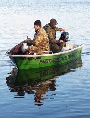 Funkcjonariusze Państwowej Straży Rybackiej płyną łodzią na jeziorze.