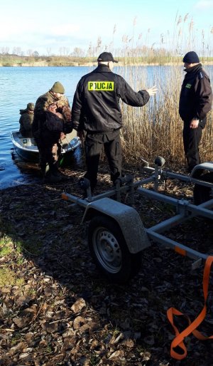 Policjanci i funkcjonariusze Państwowej Straży Rybackiej podczas wodowanie łodzi na jednym z pałuckich jezior