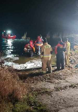 Panujący mrok. Na jeziorze pływa łódź ratunkowa w poszukiwaniu mężczyzny. Przy brzegu znajduje się kolejna oraz funkcjonariusze straży pożarnej.