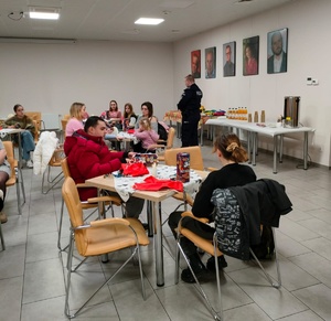 Policjant z KP Barcin szkoli wolontariuszy WOŚP. Policjant stoi przy stolikach, wokół których siedzą wolontariusze